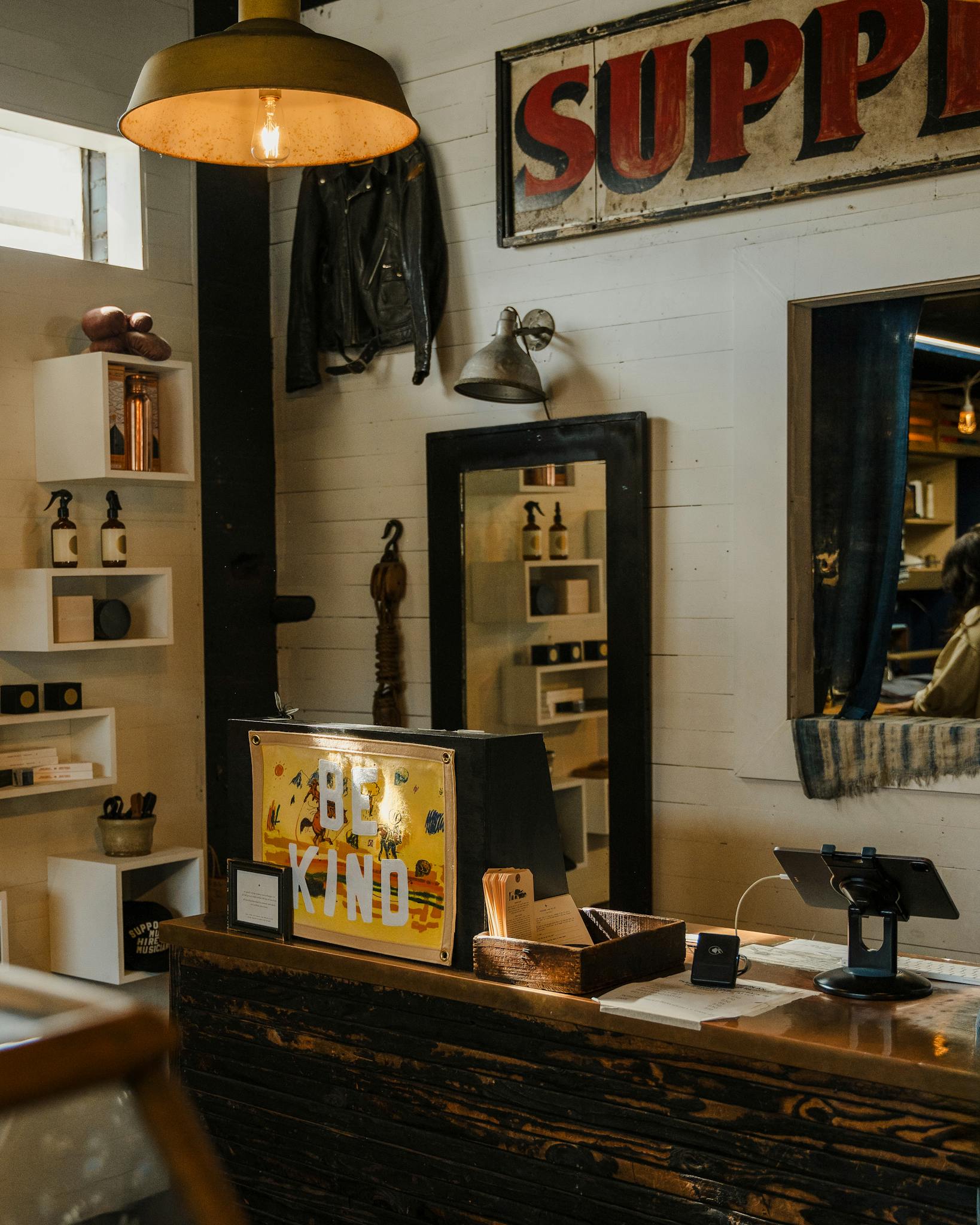 Warm vintage shop interior featuring wooden decor and 'Be Kind' sign on counter.